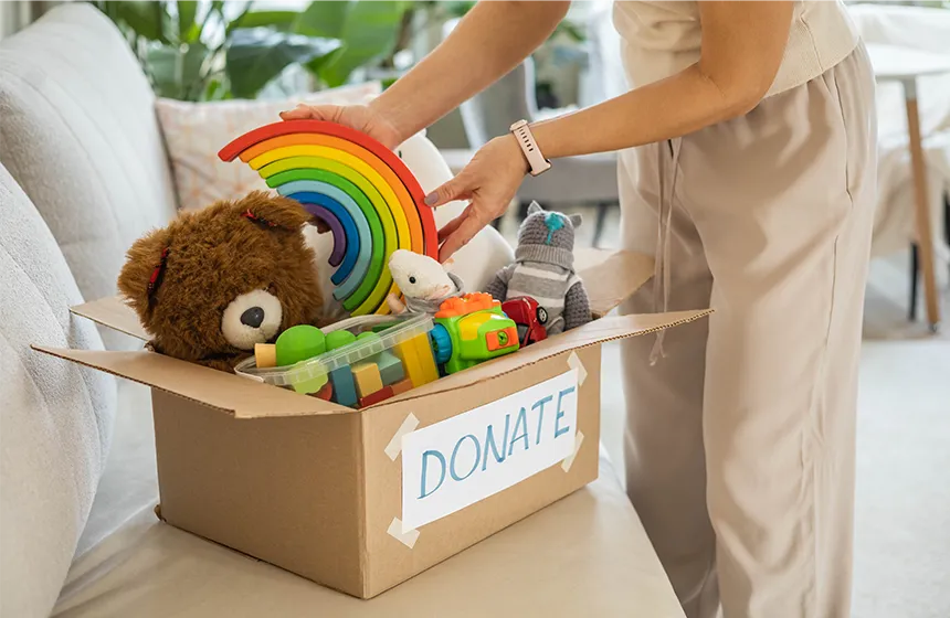A person packing kid's toys into a donation box