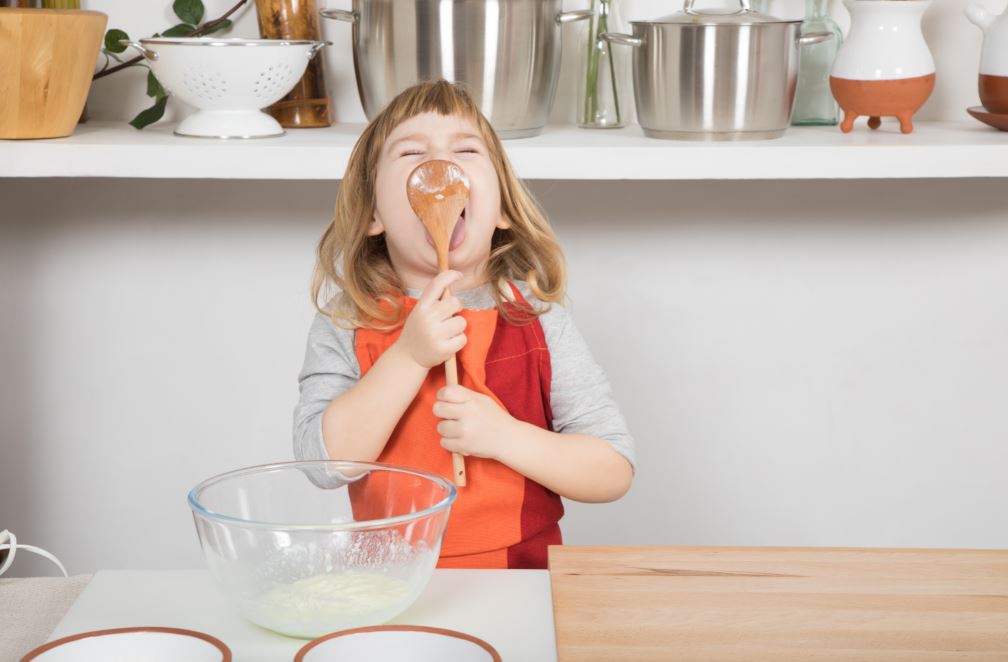 child licking spoon after cooking