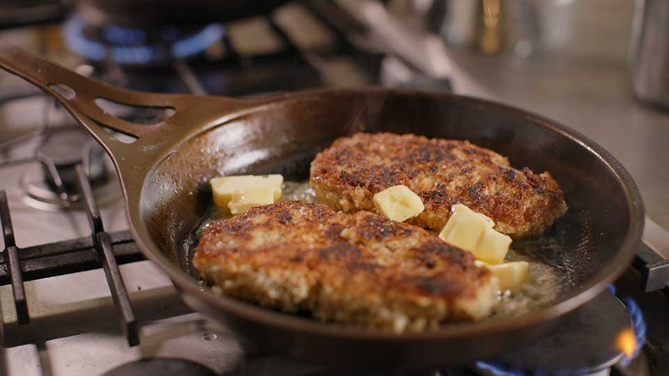 crumbed pork chop in frypan with butter